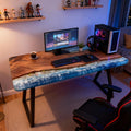 Contemporary workspace featuring a black walnut wave epoxy desk, deep ocean-blue resin swirl, and polished surface reflections.