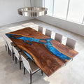 Black walnut epoxy resin table in a modern living room, featuring a deep ocean-blue river epoxy with marbled swirl and glossy finish.
