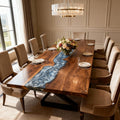 Elegant dining room scene with a black walnut river epoxy dining table, upholstered chairs, and a gold chandelier overhead.