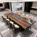 Modern dining space featuring a black walnut river epoxy dining table with vivid blue resin depth and dramatic natural wood grain.
