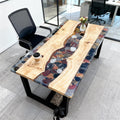 Modern workspace showcasing a French poplar epoxy resin desk with a pebble-filled clear resin creek and glossy finish.