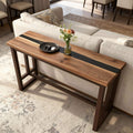 Black walnut epoxy resin console table behind a sofa, featuring a deep black resin river inlay with glossy finish and rich natural grain.
