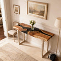 Walnut epoxy resin console table behind a sofa, featuring a deep black resin river inlay with glossy finish and rich natural wood grain.